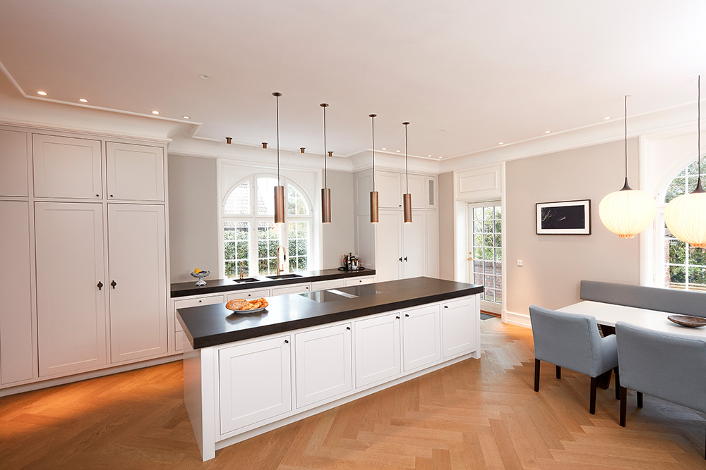 Helhedsindtrykket er holdt klassisk med sprøjtemalede elementer i glans 50 og to styk Nero Assoluto bordplader i massiv granit.