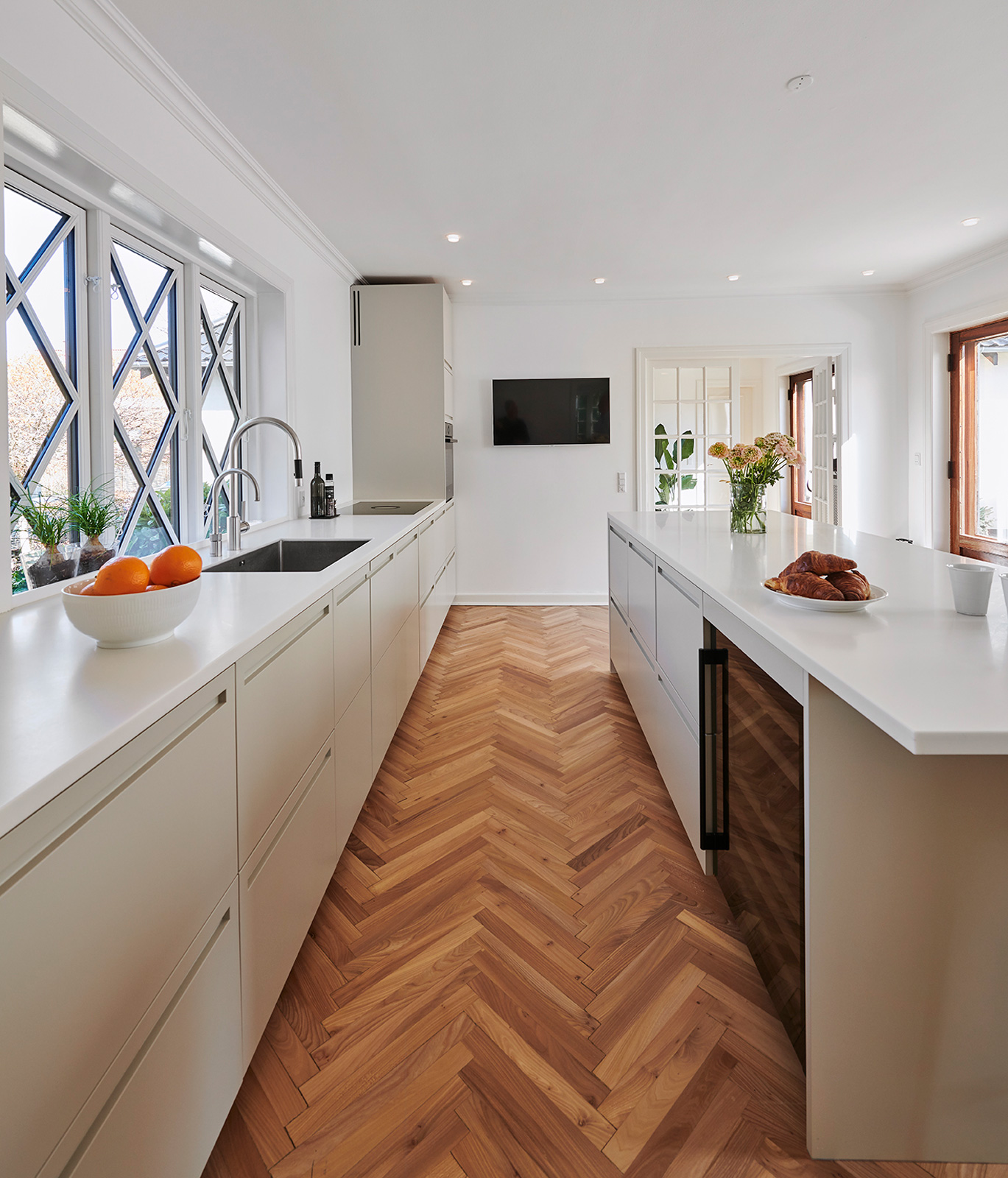 De hvidmalede elementer og bordpladerne i hvidpigmenteret ask får et fint modspil af væggens grønne nuance.